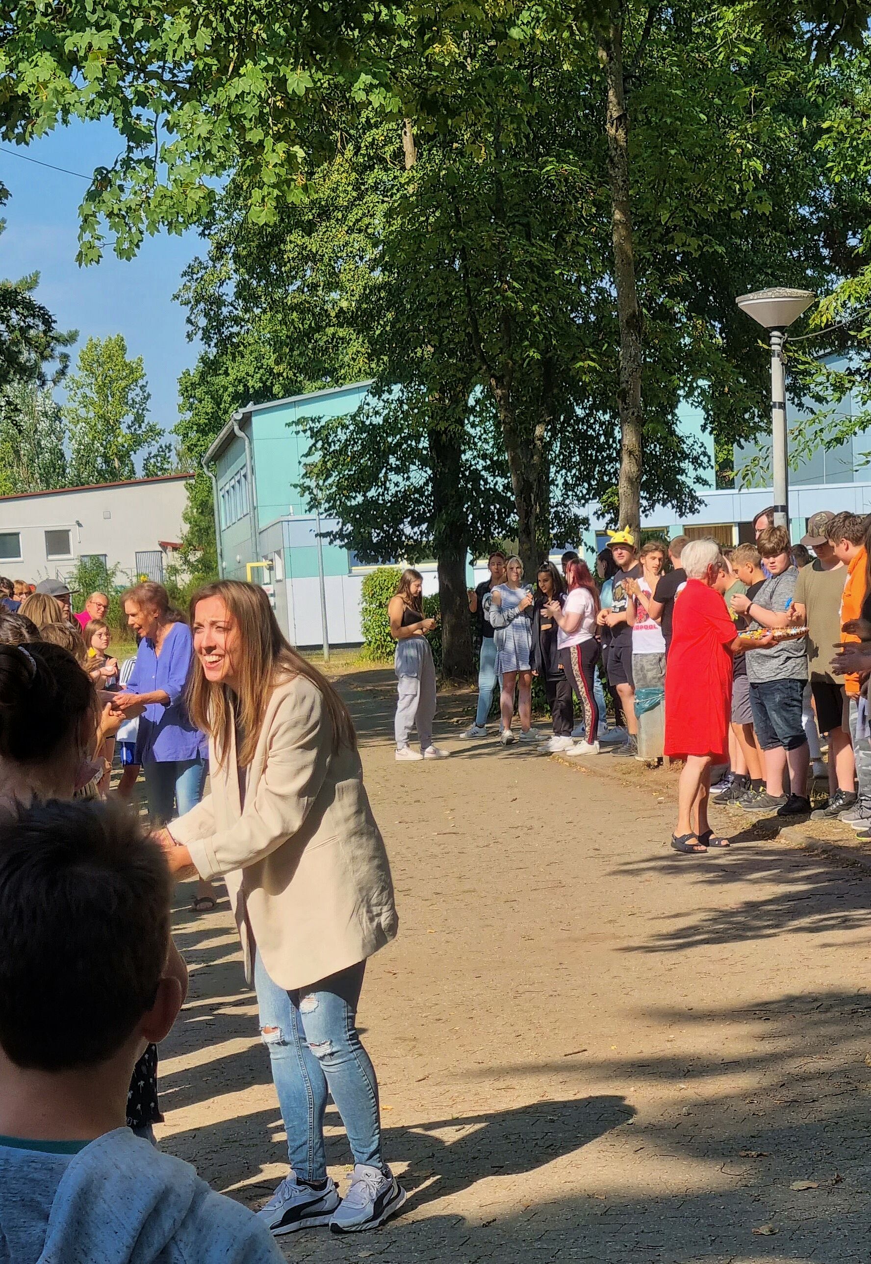 Die Schülerinnen und Schüler stehen am Pausenhof Spalier. Es werden Süßigkeiten verteilt.