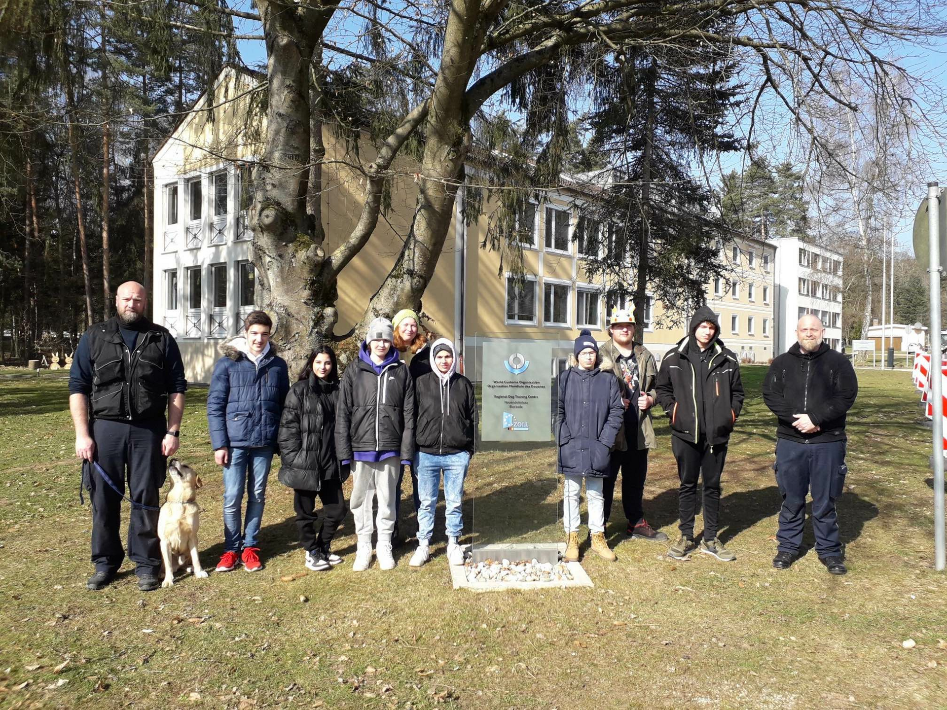 Die Klasse steht vor der Zollhundeschule mit Max, dem Labrador.