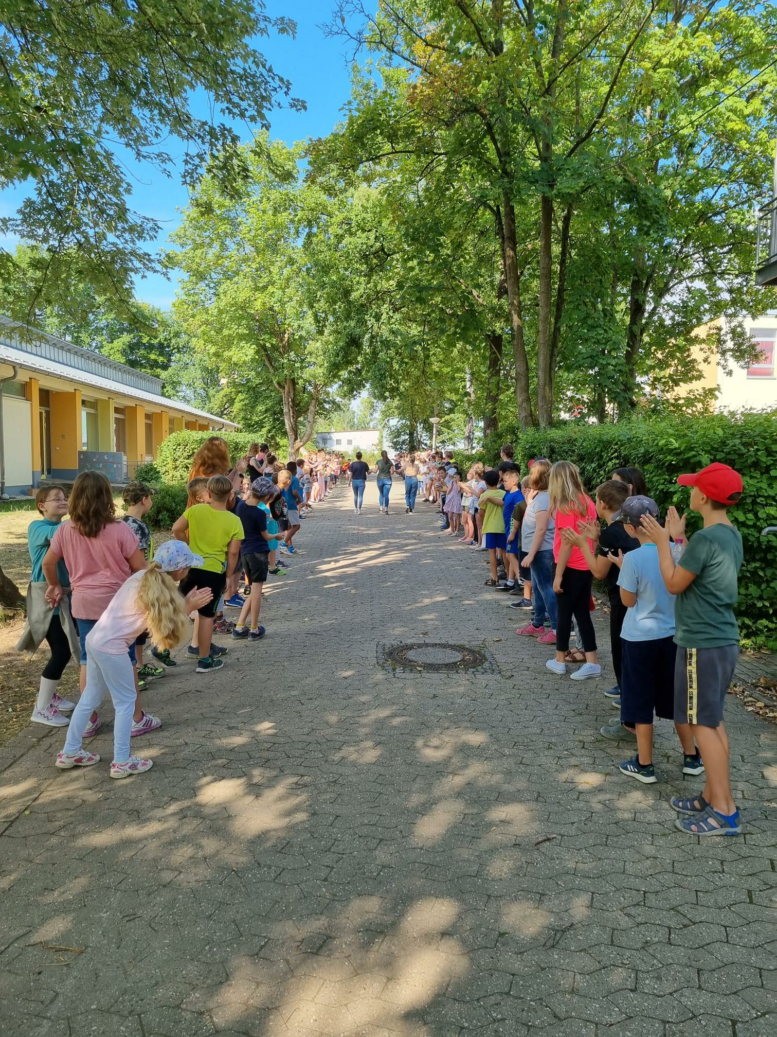 Schülerinnen und Schüler stehen am Pausenhof Spalier.